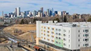 A drone shot of the denver city skyline on a sunny day with Arroyo village in the foreground